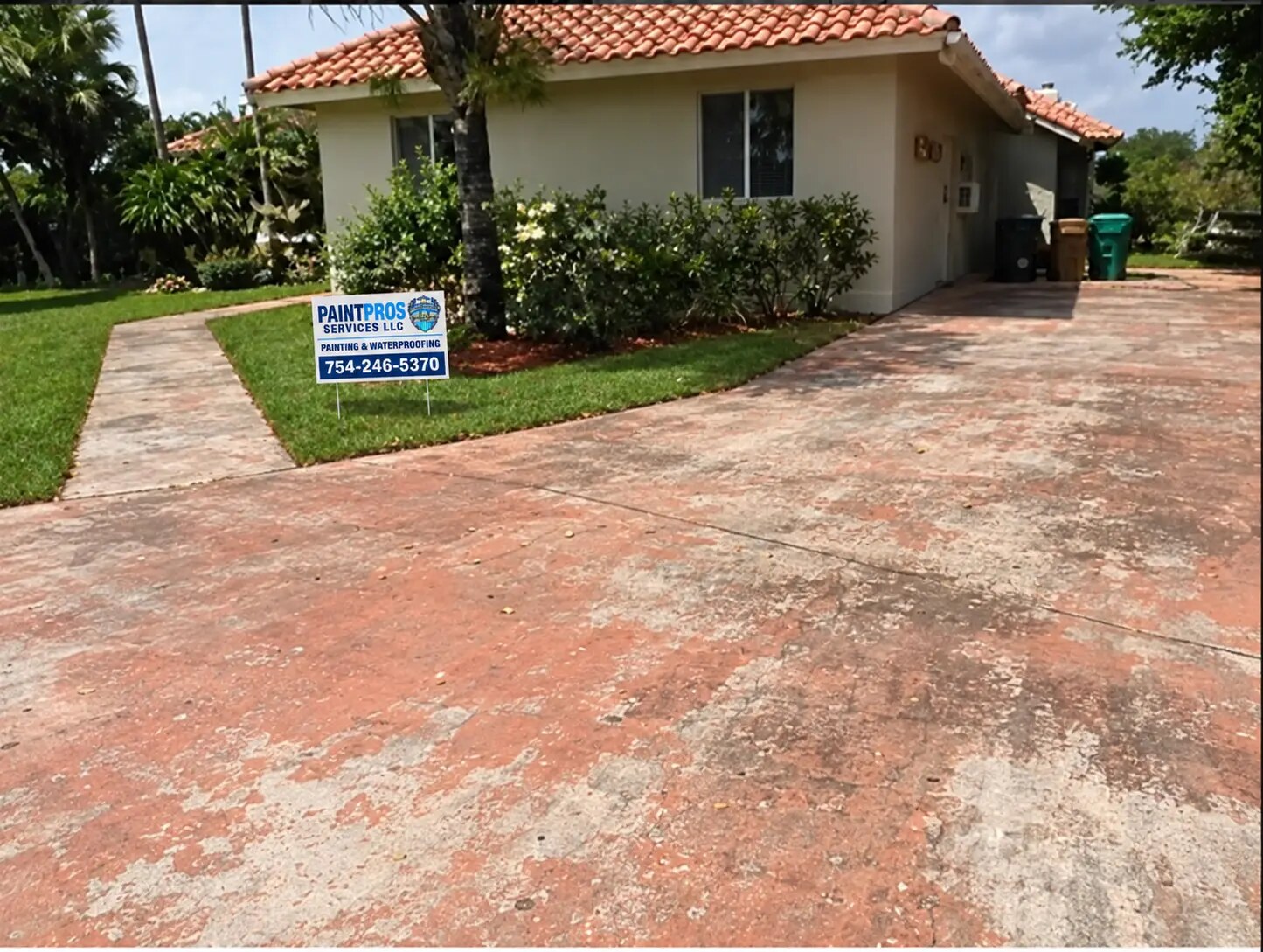 Same residential driveway with a faded and worn terracotta finish before recoating and the approved PaintPros yard sign