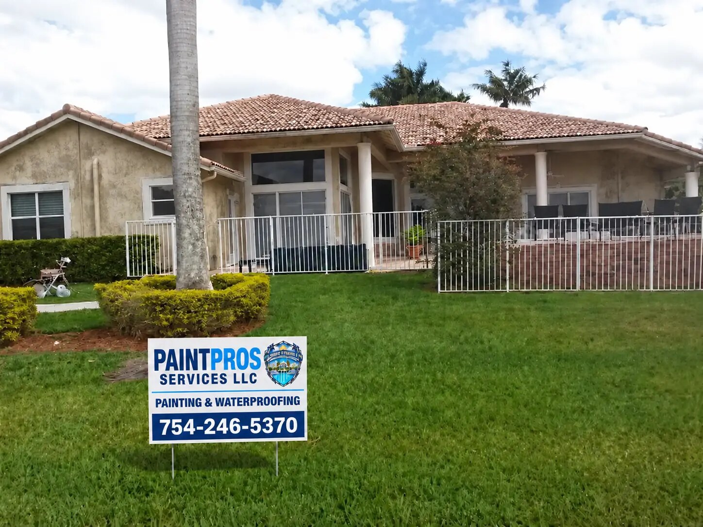 Same rear patio house with faded and weathered exterior paint before repainting and the approved PaintPros yard sign